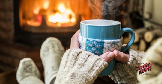 A homeowner sitting in front of the fireplace with a cup of coffee.