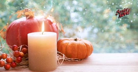 A candle and pumpkins being used as fall decorations in a home.