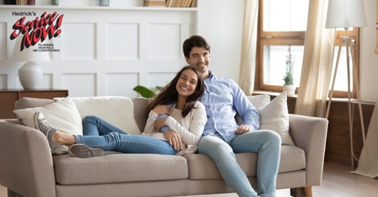 Young couple sitting on couch of semi empty apartment.