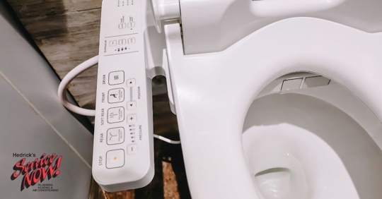 Image of a toilet with bidet attachment displaying several buttons.